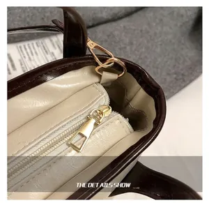 Close-up of golden hardware and zipper detail on a bicolor brown and cream bucket bag