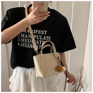 Detail of cream PU leather bucket bag featuring a miniature baseball glove keychain charm