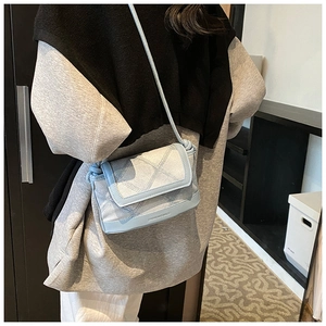 Detail of light blue crossbody bag with denim texture, stitching and logo
