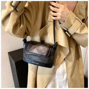 Detail of vintage plaid crossbody bag worn with trench coat showing the unique logo print