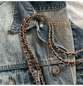 Gros plan d'une bandoulière en cuir marron et chaîne argentée sur fond en denim bleu