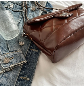 Vue de dessus d'un sac bandoulière matelassé marron foncé avec fermoir argenté et chaîne