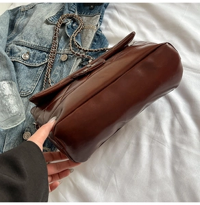 Détails de la texture matelassée café et de la bandoulière en chaîne de cuir du sac