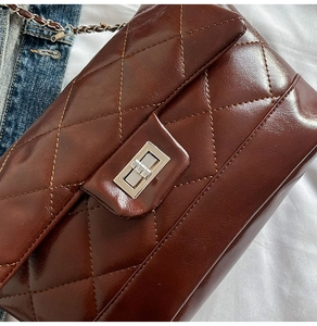 Détail de la texture cuir matelassé marron et du fermoir en métal argenté du sac
