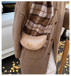 Sac croissant beige chic avec finition brillante et détails dorés porté par un mannequin