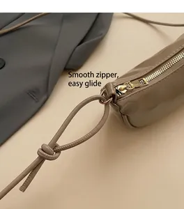 Gros plan sur la fermeture éclair dorée et la bandoulière nouée du sac en cuir marron