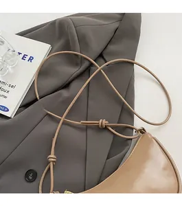 Détail d'un sac demi-lune beige avec bandoulière fine nouée et cuir PU à l'aspect lisse