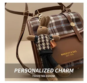 Close-up of a vintage plaid backpack with brown leather accents and a cute bunny charm