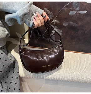 Détail du sac demi-lune marron foncé en cuir verni brillant avec zip doré