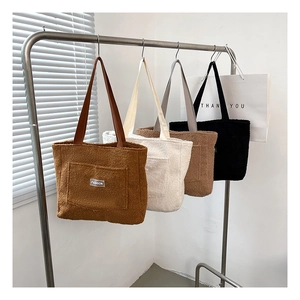 Detail view of large sherpa tote bags in four colors with fashion labels on metal hangers