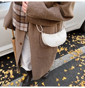 Détail du sac croissant blanc avec lettrage doré dans un décor d'automne en plein air