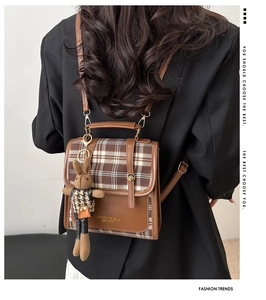 Detail eines Vintage-Karo-Rucksacks aus braunem PU-Leder mit Plüsch-Hasen-Anhänger