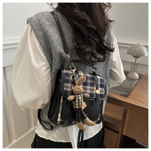 Detail of retro plaid backpack with a cute knitted bunny charm and metal buckle