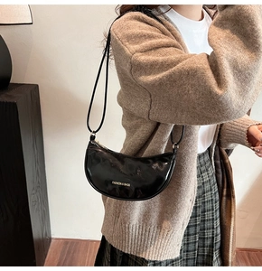 Sac à bandoulière croissant noir chic en similicuir brillant porté avec un cardigan en maille