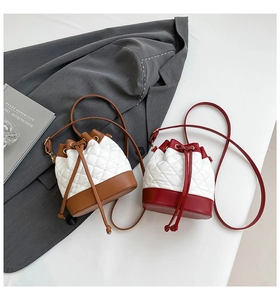 Flat lay of quilted bucket bags in brown and red with drawstring closure on gray fabric