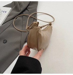 Gros plan d'un sac hobo en similicuir camel avec fermeture éclair sur fond minimaliste
