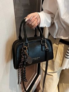 Chic black Boston handbag with tennis racket pendant and striped knot detail