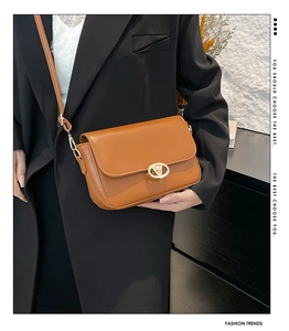 Détail d'un sac bandoulière en cuir marron avec boucle métallique ovale dorée en forme de V