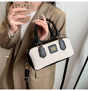 Detail of retro Boston bag in beige canvas with black leather trim and gold metal buckles