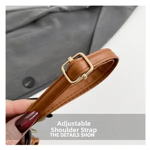 Détail de la bandoulière réglable en cuir marron avec boucle dorée sur le sac