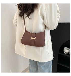 Vue arrière du modèle avec sac sous le bras marron, fermoir doré et bandoulière fine