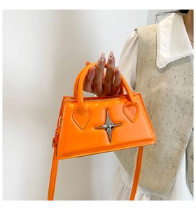 Détail du sac trapèze orange vif avec boucle étoile argentée et finition cuir lisse