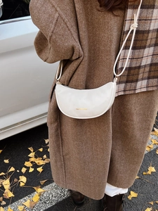 Sac à bandoulière blanc en forme de croissant avec inscription dorée et style épuré