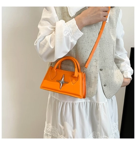 Détail d'un mini sac en cuir PU orange vif avec emblème étoile argenté et bandoulière