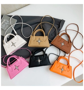 Top view of six multi-colored trapezoid handbags with silver star emblem on a textured surface