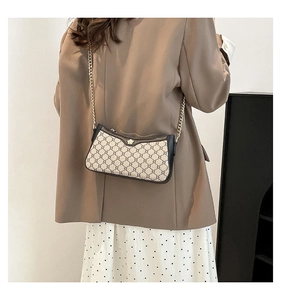 Detail of vintage pattern shoulder bag with metallic flower clasp and gold chain strap