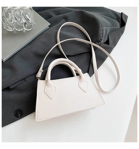 Detailansicht der cremeweißen Trapez-Handtasche mit runden Griffen auf Marmor