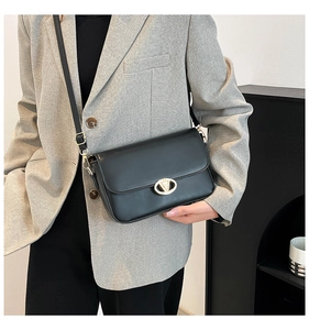 Détail du sac à bandoulière en cuir noir avec une boucle métallique en V dorée élégante