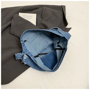 Detail view of large denim tote bag interior featuring an inner pocket and frayed edges