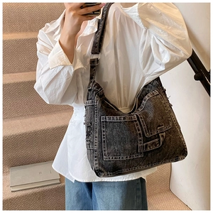 Close-up of distressed charcoal denim bag featuring multi-pocket workwear design