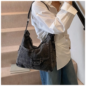 Detail view of washed black denim tote bag with vintage pockets and distressed frayed edges
