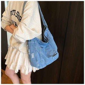 Close-up of distressed blue denim tote bag with multi-pocket design and retro frayed details