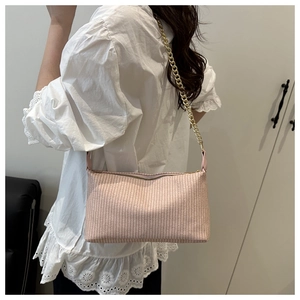 Detail of pink woven pillow bag with gold chain strap shown on a shoulder