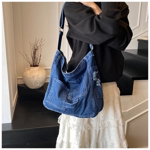 Detail of blue denim tote bag with vintage frayed edges and adjustable metal strap