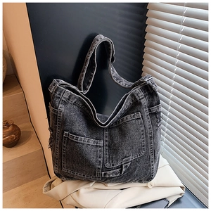 Detailed view of deep gray denim tote bag featuring large front pockets and fringe trim