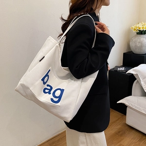 Minimalist white canvas tote bag with blue 'bag' print and large capacity for daily use