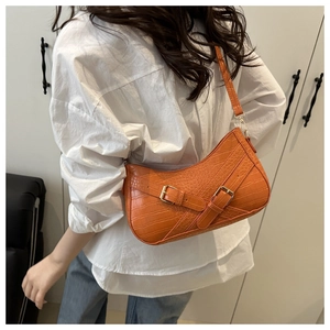 Detail of orange faux leather shoulder bag with crocodile pattern and metal buckles