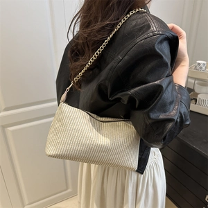Minimalist woven pillow bag with gold chain strap shown on model in a casual indoor setting