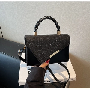 Détail du sac bandoulière noir avec boucle en métal doré et rabat à paillettes brillantes