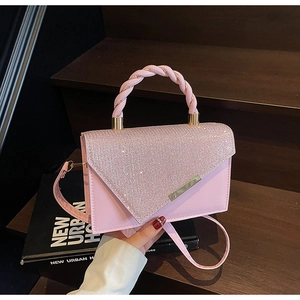 Close-up of pink crossbody bag with sparkling rhinestones and woven top handle