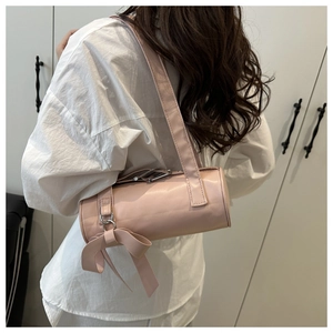 Pink cylinder bag featuring a large decorative bow and polished silver metal hardware