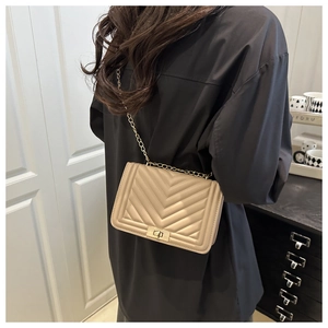 Close-up of beige quilted leather bag with gold twist lock and metal chain strap