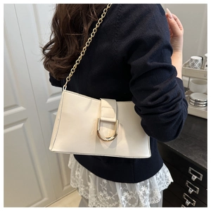 Detailed shot of cream faux leather bag featuring a large gold U-shaped metal buckle