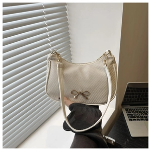 Detailed view of the woven crescent bag featuring a gold bow accent and leather trim
