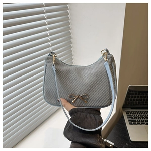 Detail of grey woven crescent bag with light blue strap and gold bow metal buckle