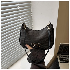 Detailed view of black woven moon bag with golden bow hardware and leather strap